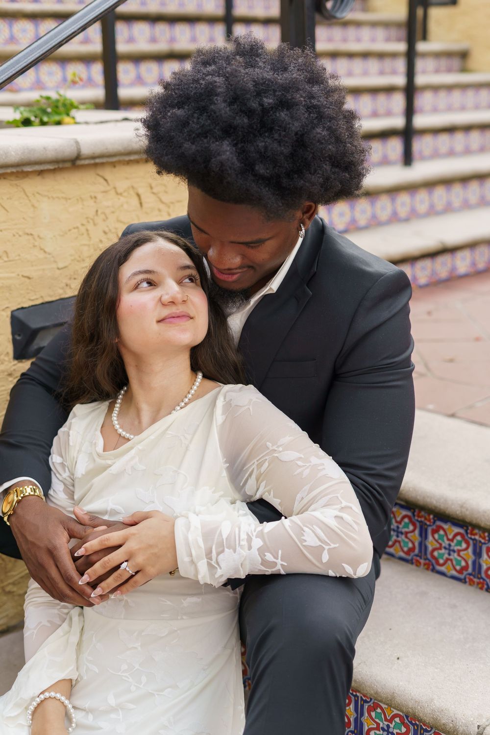 A romantic couple shares intimate moments while sitting on decorative tiled steps.