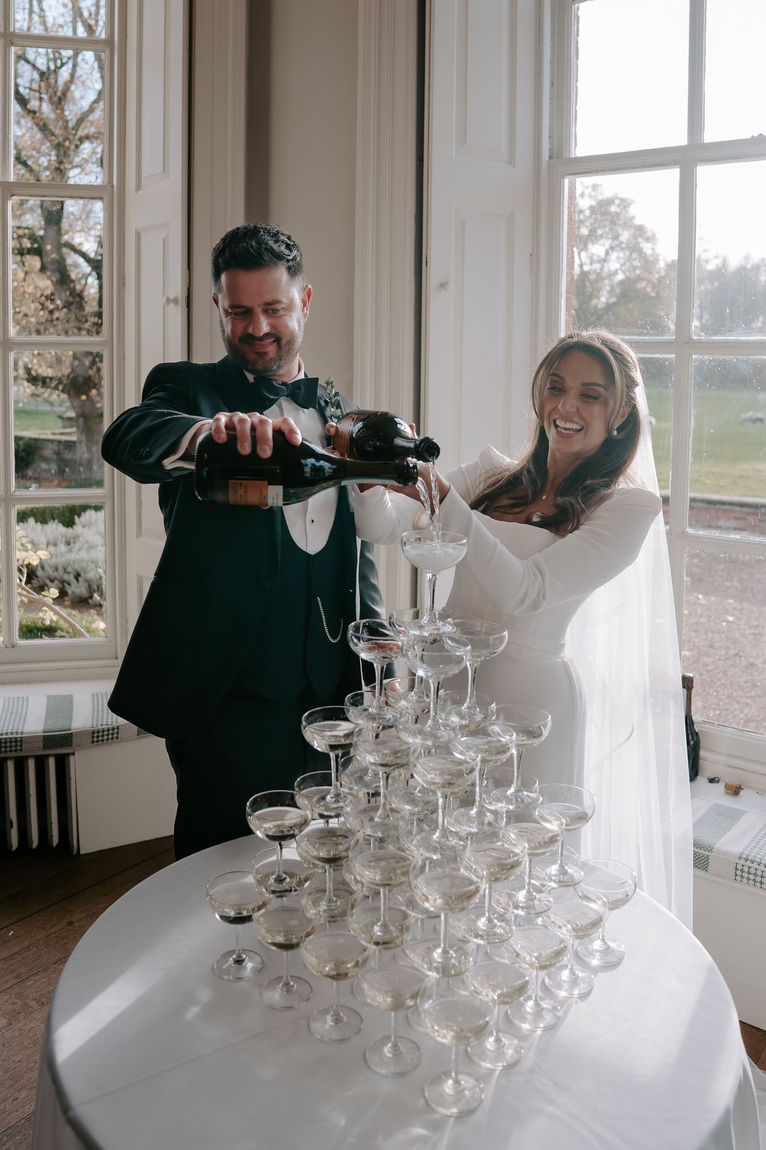 bride and groom pouring champagne into a champagne tower at iscoyd park