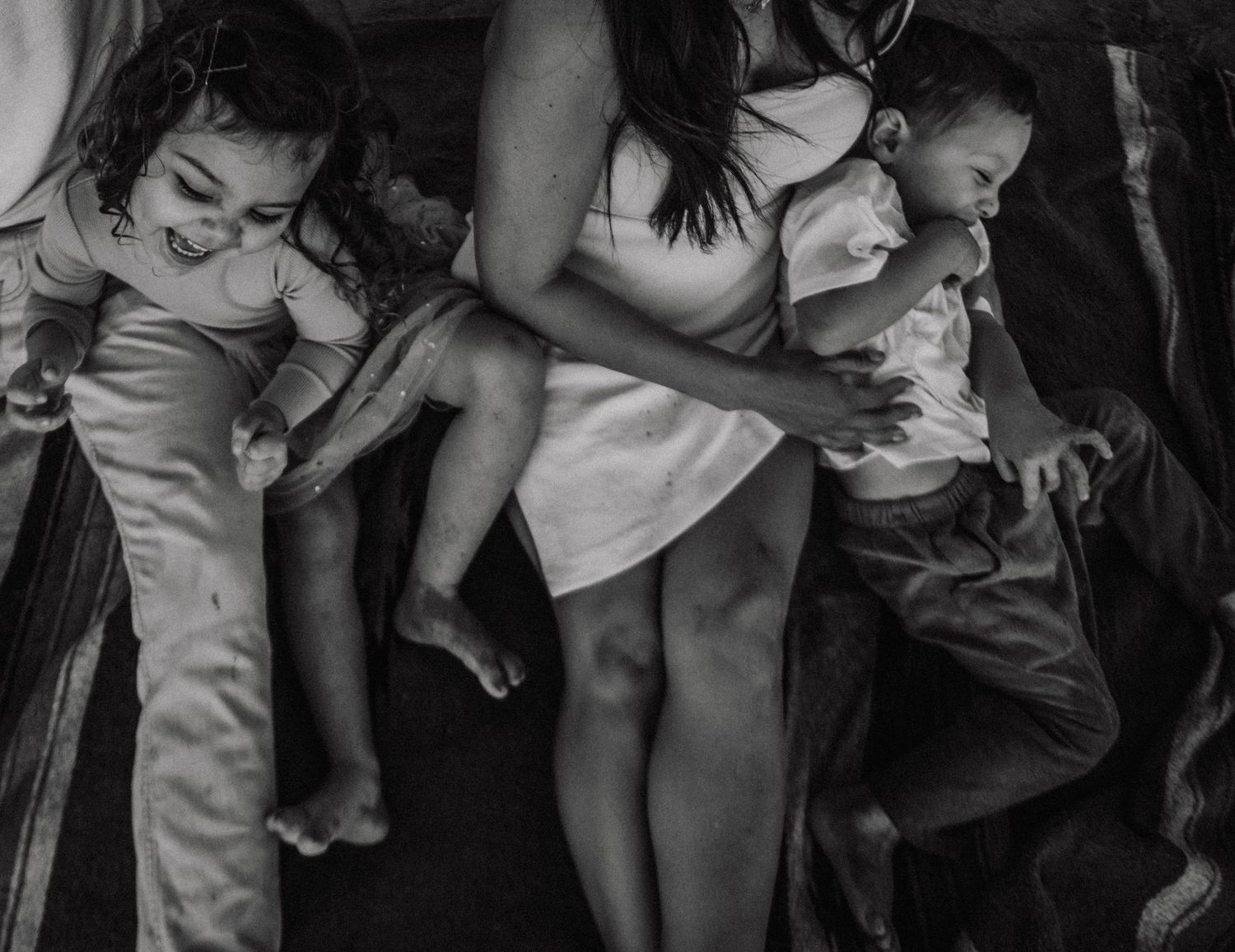 Black and white intimate photograph of sleeping family members nestled together.