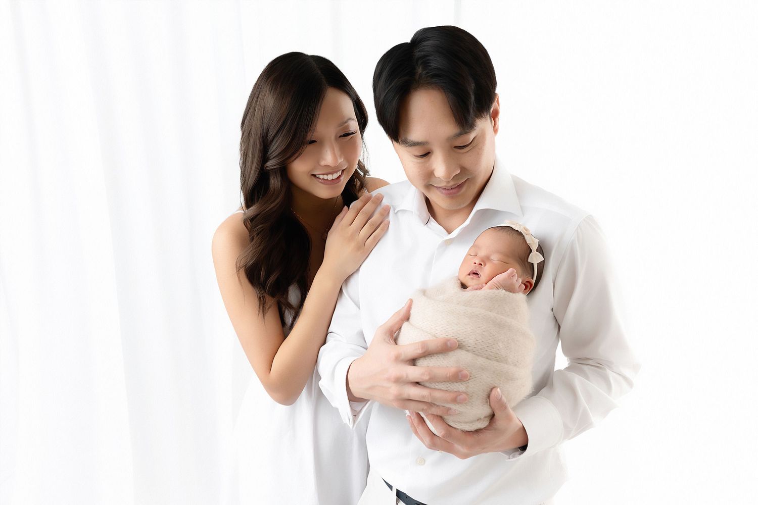 A series of tender family portraits in white showing parents holding and bonding with their newborn baby.