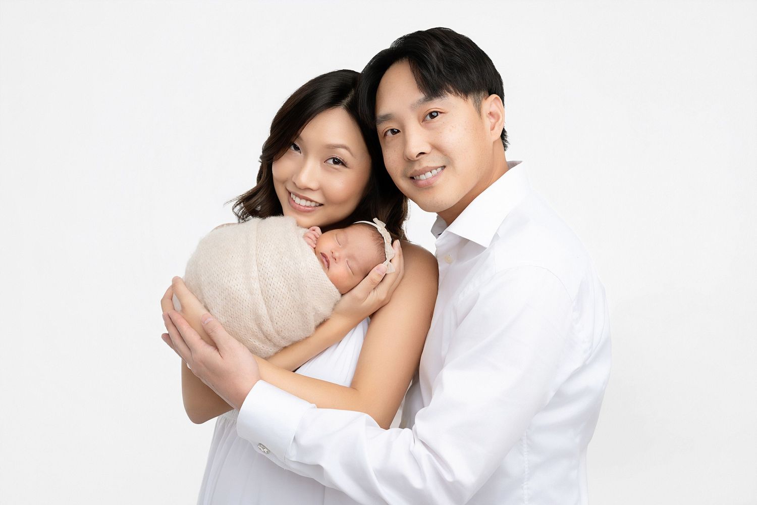 Happy couple in white embraces tenderly while sitting together in studio setting.