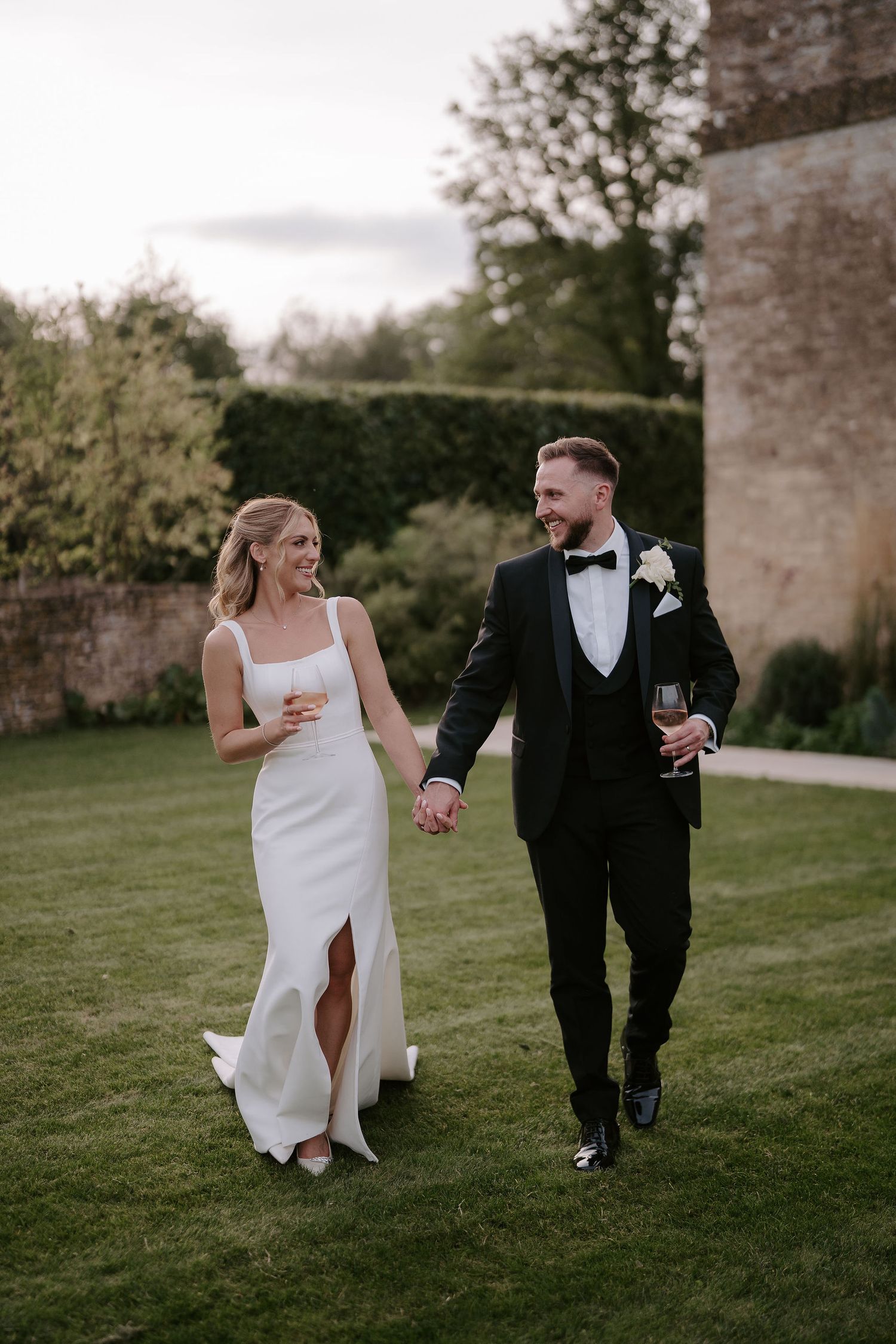 bride and groom walking and smiling at ivy lodge wedding in cirencester