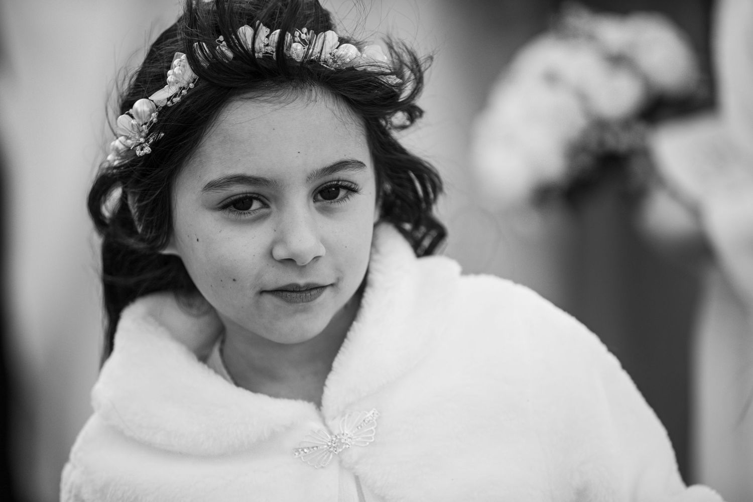 Black and white portrait of a young person wearing a white wrap and floral crown in their dark curly hair.