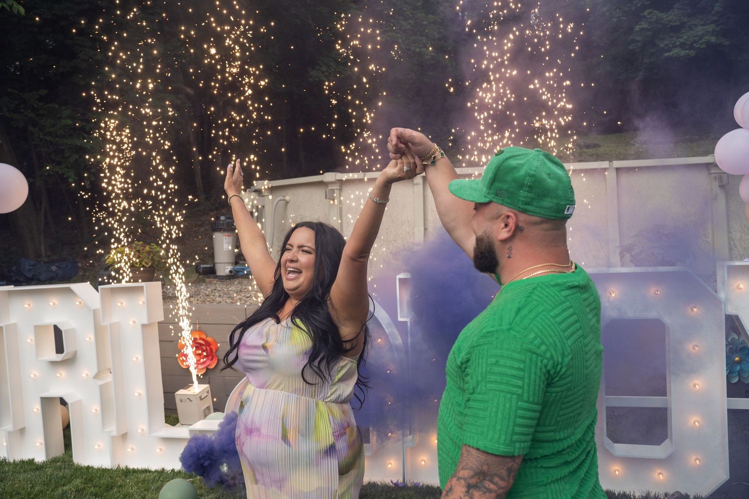 A group of people celebrate with sparklers and confetti in an outdoor party setting at night.