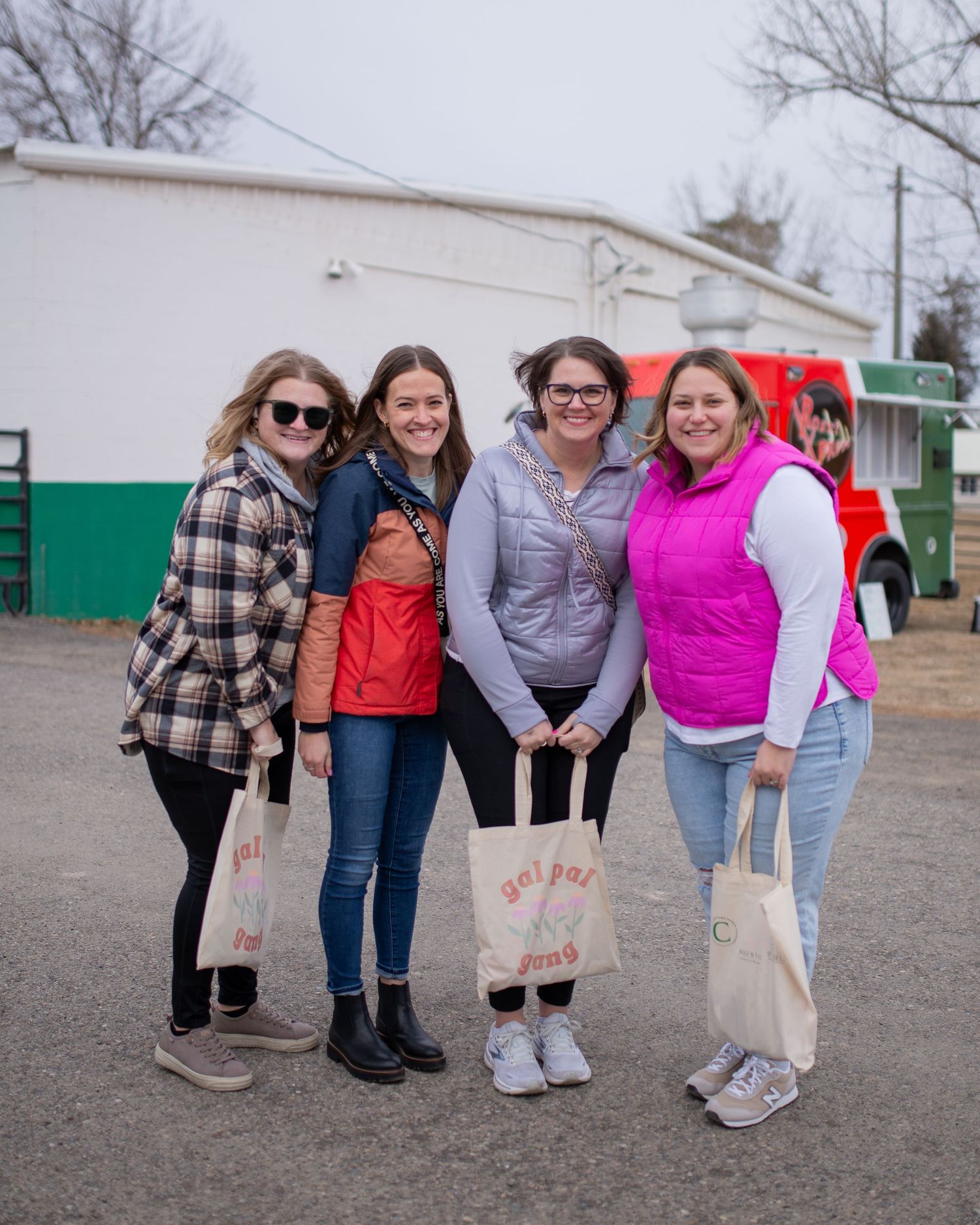 Four women are bundled up and holding swag tote bags from the vendor market event "Gal Pal Collective" at the fairgrounds in Filer, Idaho.