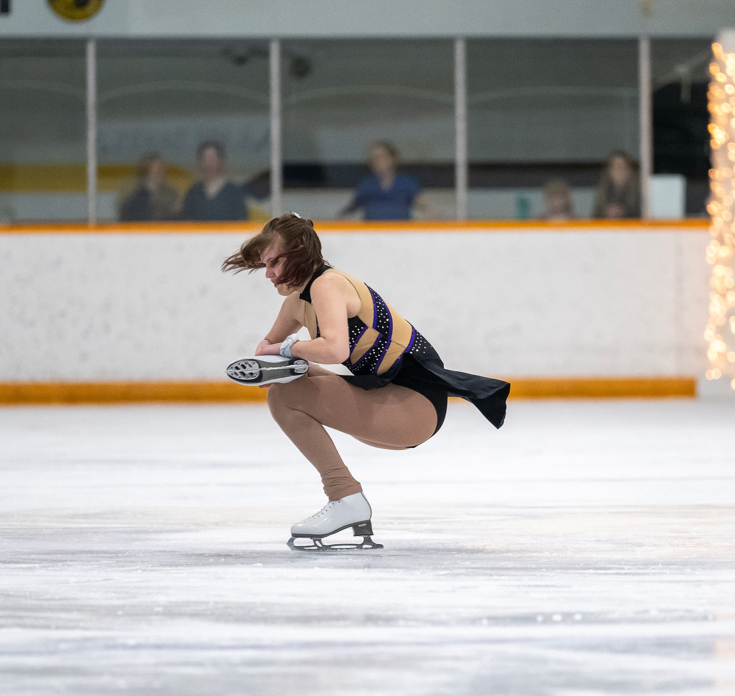 Figure skater performs graceful spin sequence on ice during competition routine, showcasing elegant form and technique.