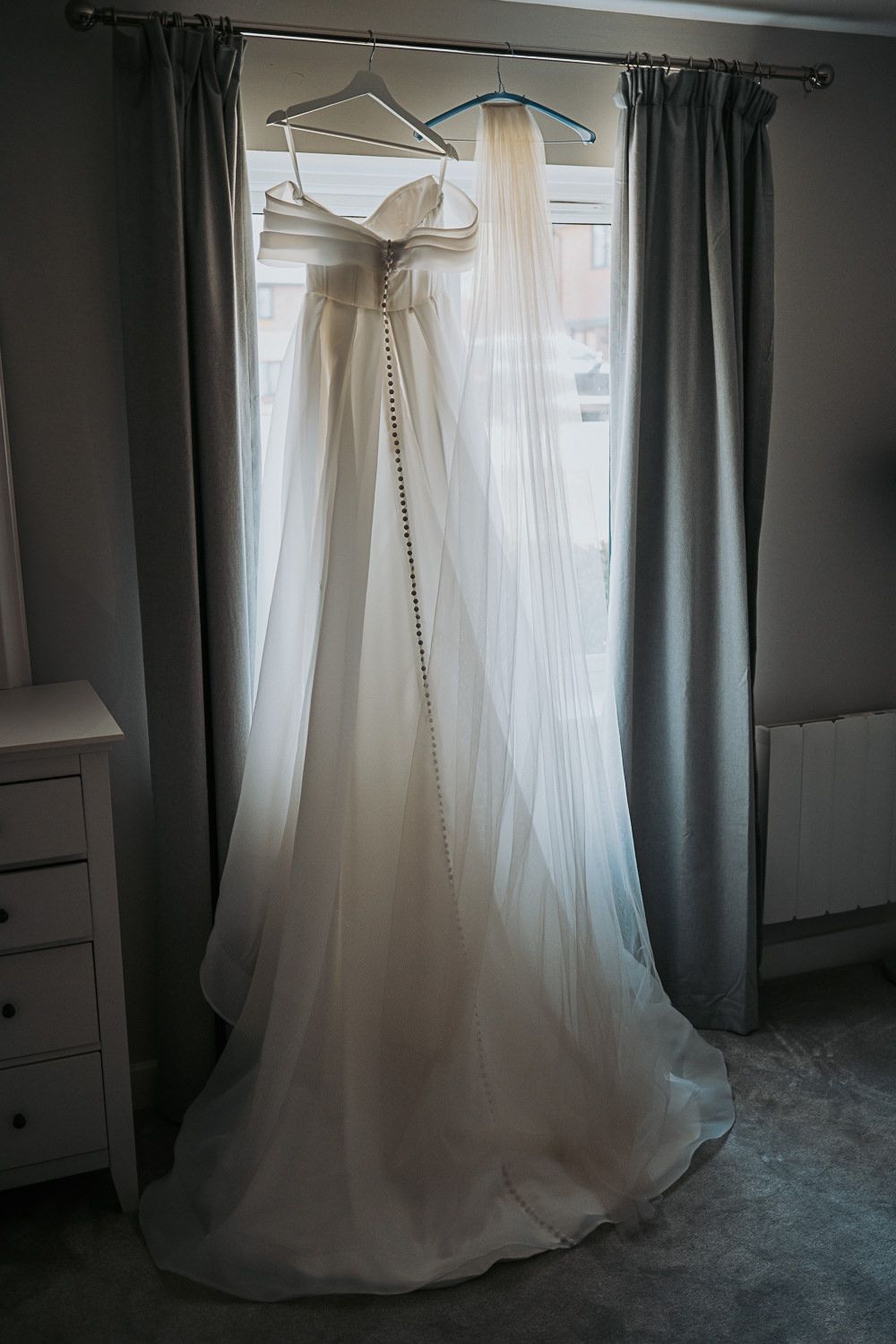 Multiple views of an elegant white wedding dress hanging in a room with gray curtains and natural lighting.