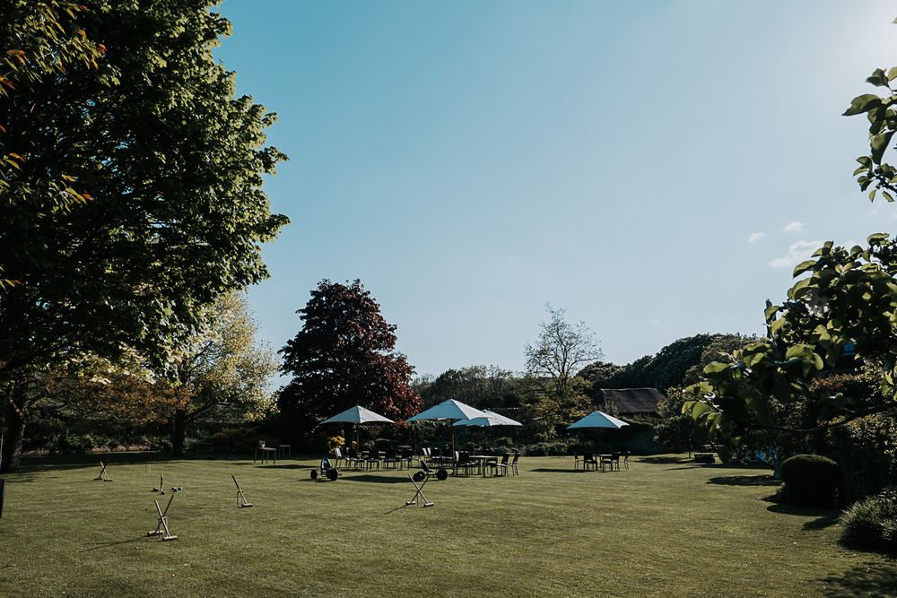 People enjoying a sunny day on a spacious green lawn with trees surrounding the perimeter and a gazebo in the distance.