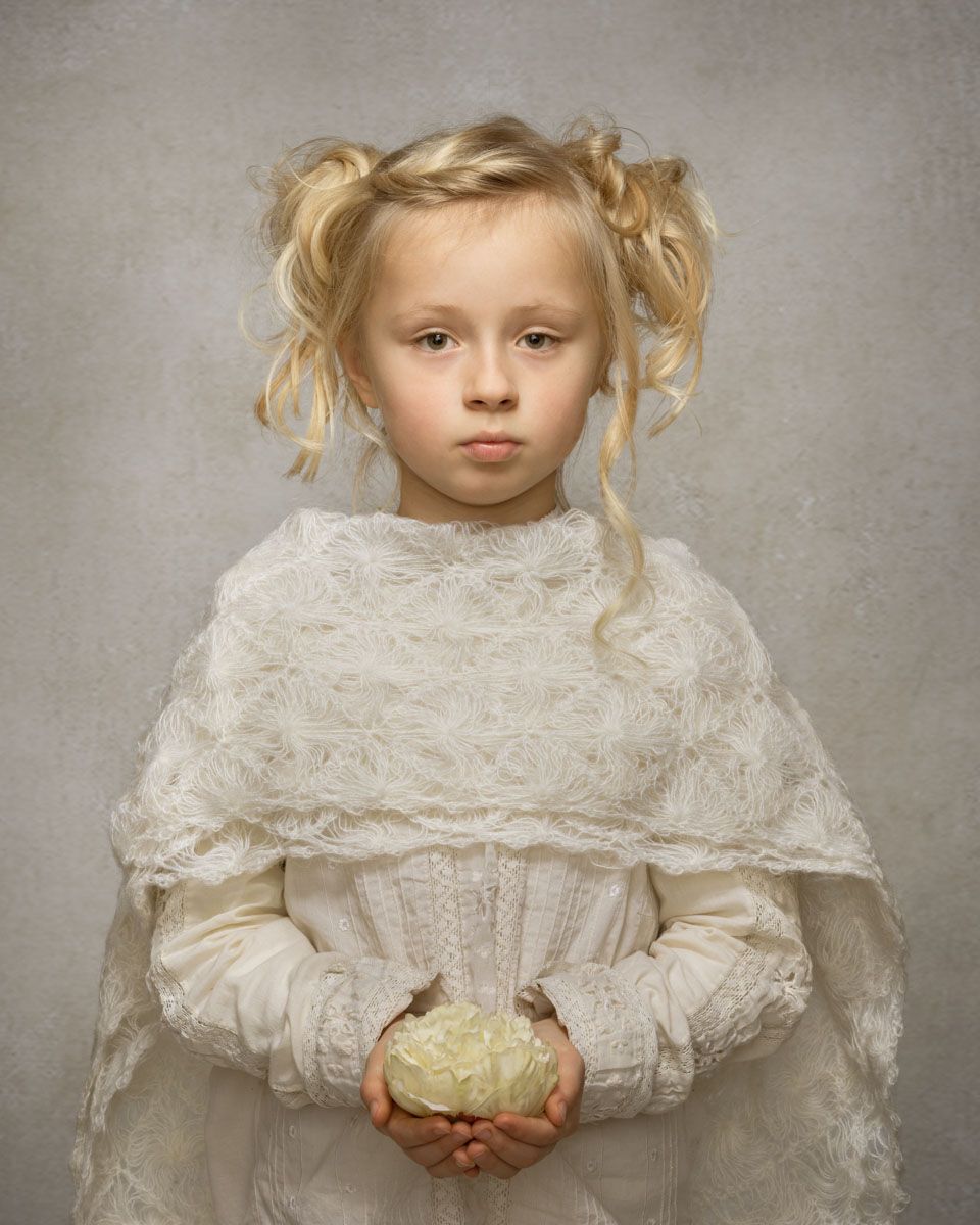 Striking fine art portrait of little girl, styled in timeless attire and with lavish hairstyle