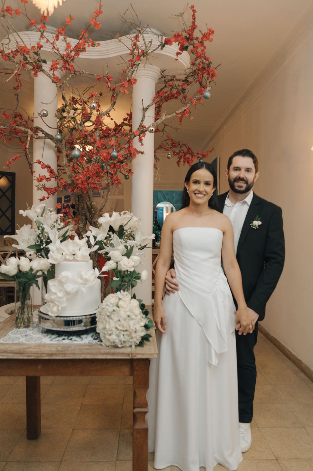 An elegant wedding scene with a white cake display decorated with coral branches and white flowers.