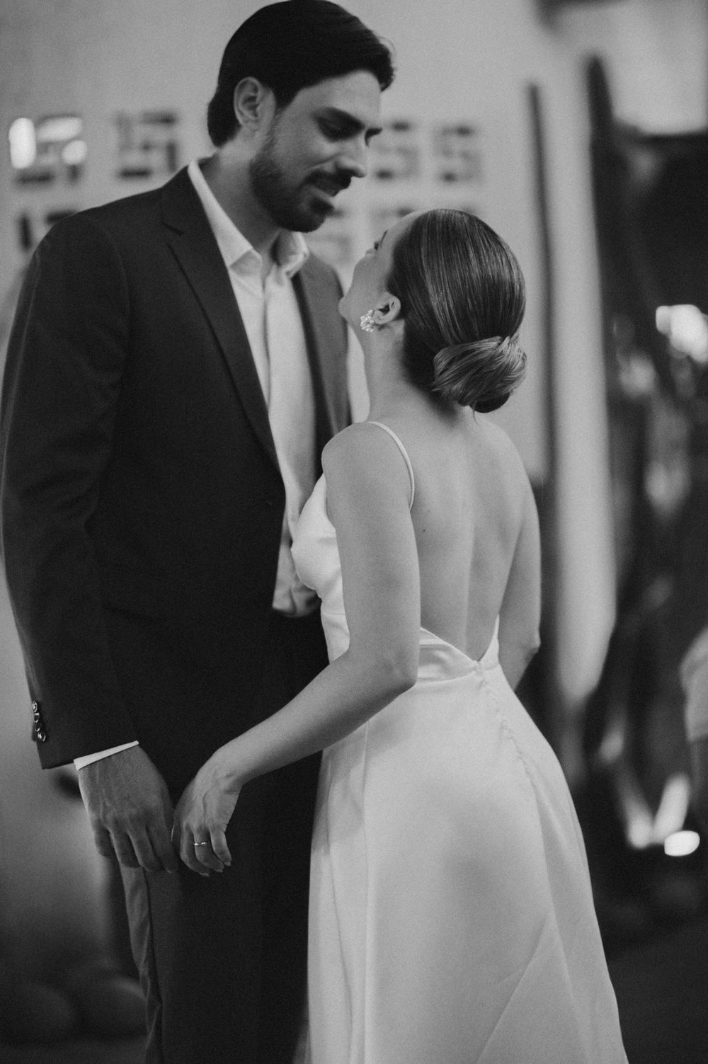 A couple in formal wedding attire share an intimate moment in black and white photography.