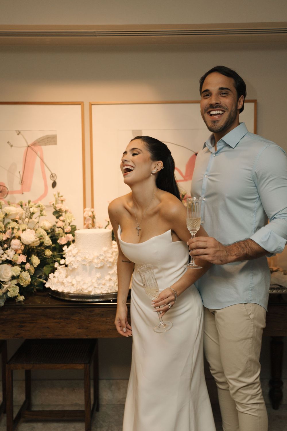 A couple shares a joyful moment together while cutting their wedding cake at an intimate reception.