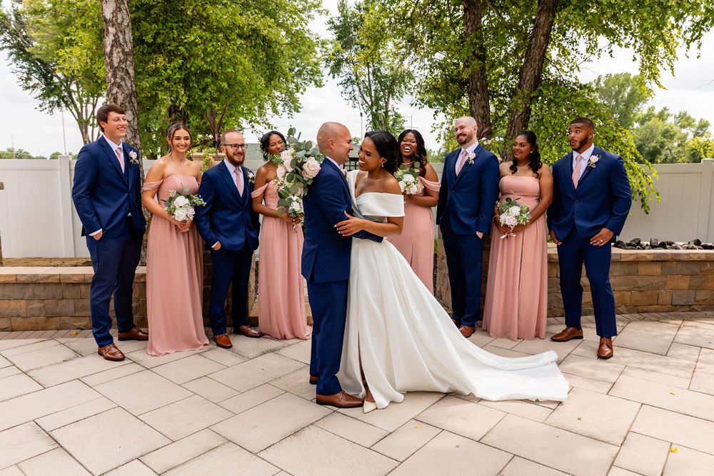 Wedding party in navy suits and blush pink dresses poses together on stone terrace at Villa Aletta in Omaha, NE.