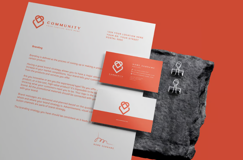 Modern business stationery set featuring coral red and white color scheme with minimalist logo designs on paper materials. Graphic Design