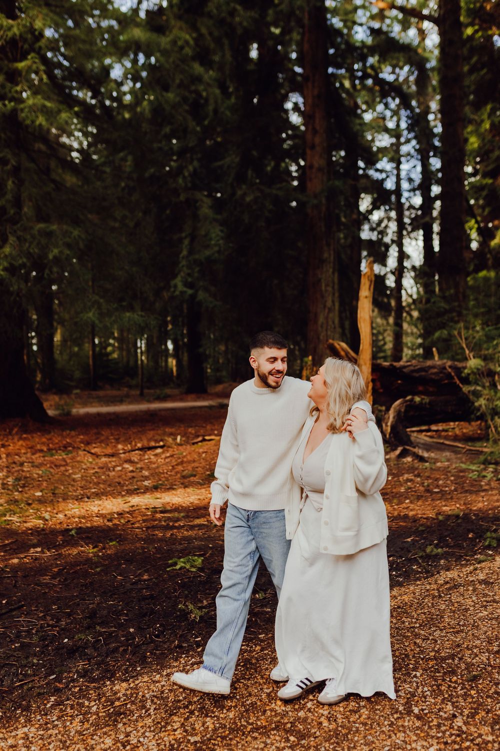 Hannah and Jordan are walking hand in hand along a woodland path.