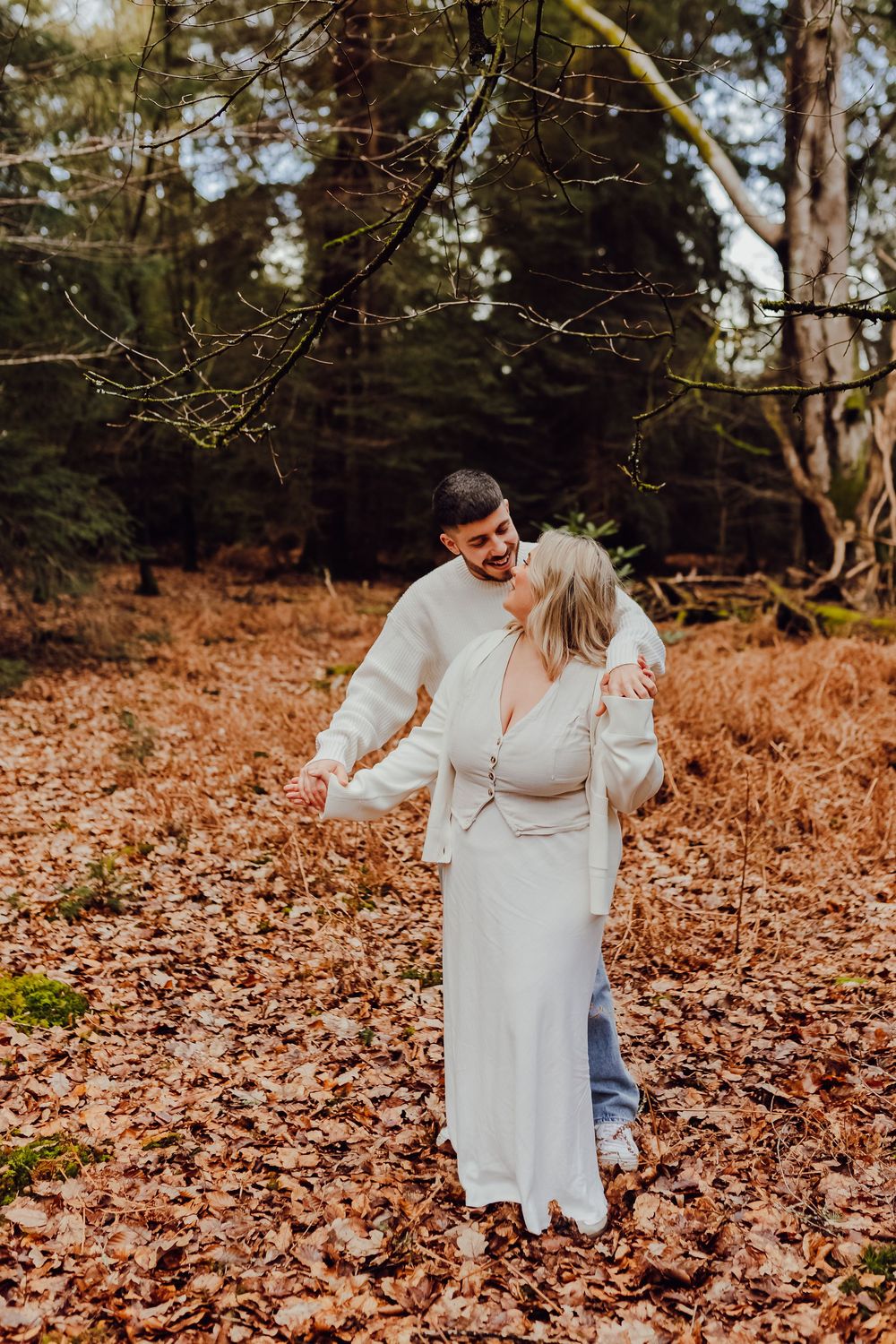 Natural engagement photo of a couple standing together in a countryside setting.
