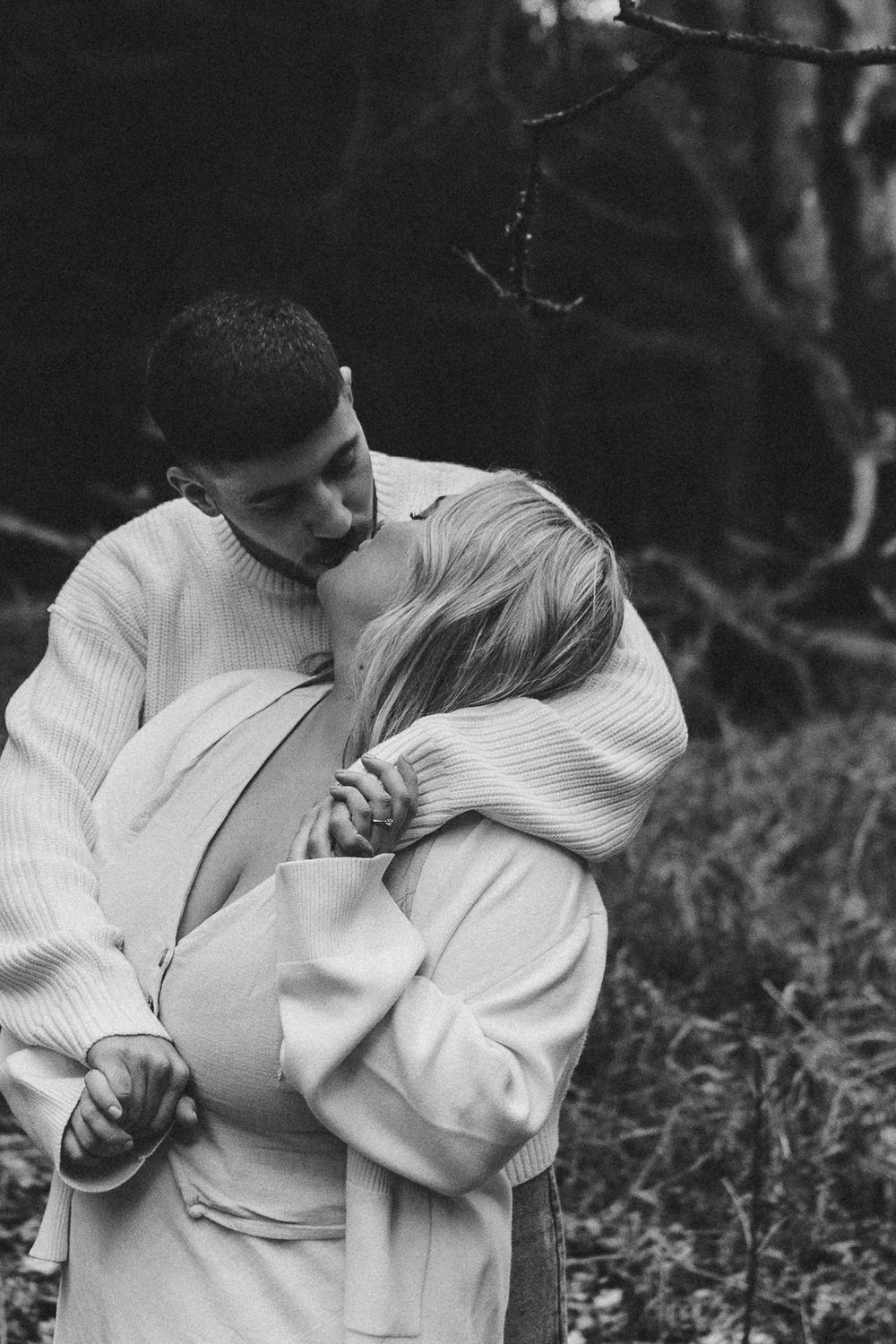 Hannah and Jordan are walking hand in hand through woodland during their February engagement session.
