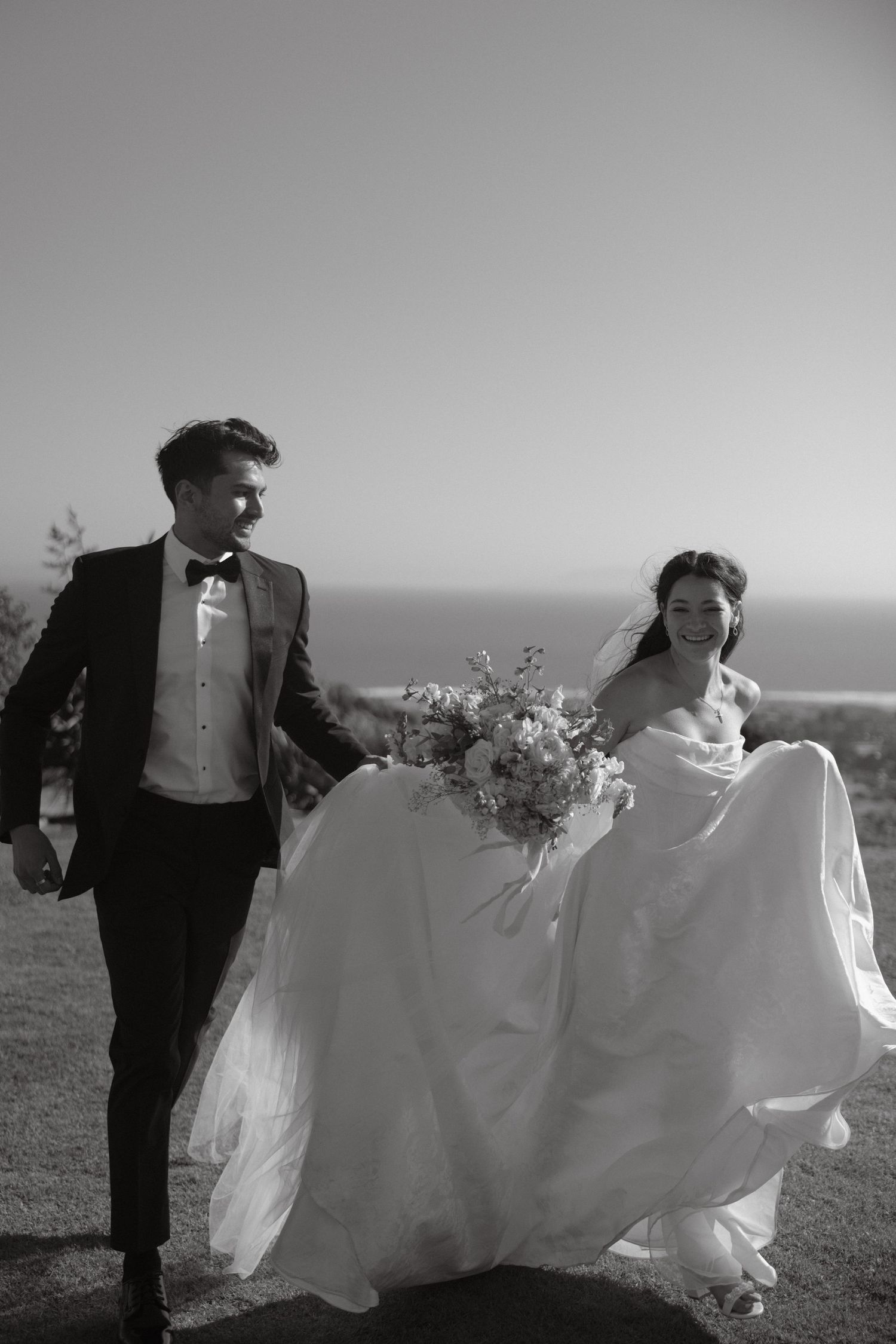 Black and white wedding portrait of a couple running along the Ventura coastline