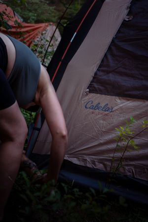 A tent with Cabela's logo is shown while someone sets up camp in the outdoors.