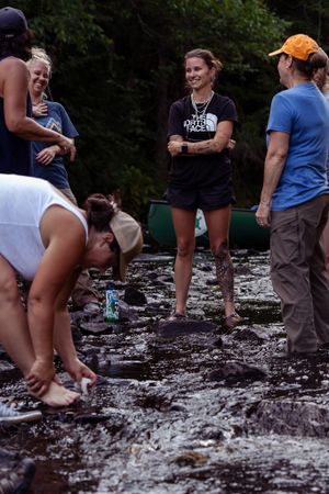 A group of people exploring a shallow rocky stream or riverbed during an outdoor activity.