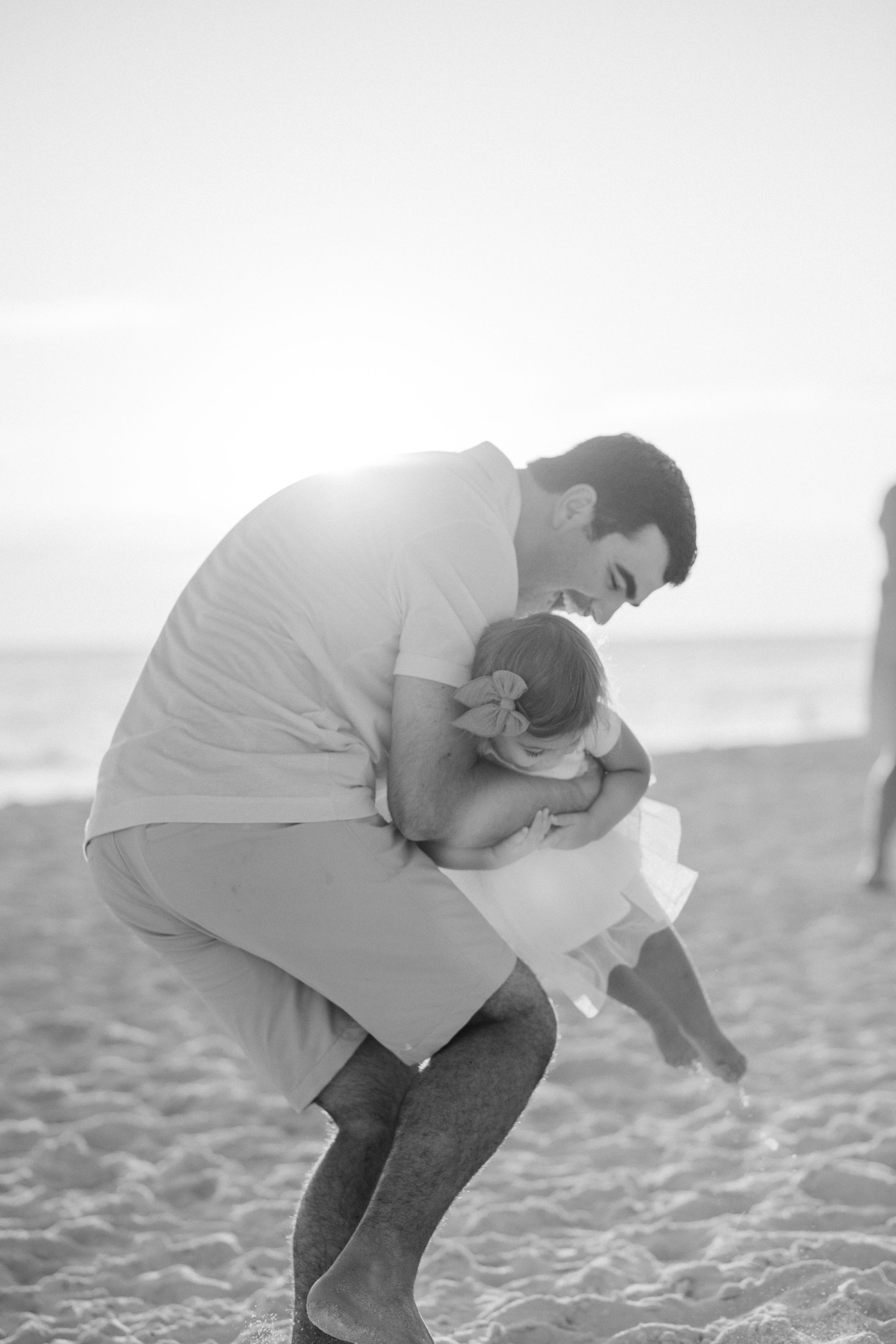 A heartwarming black and white photo of a tender parent-child moment together on a sandy beach.
