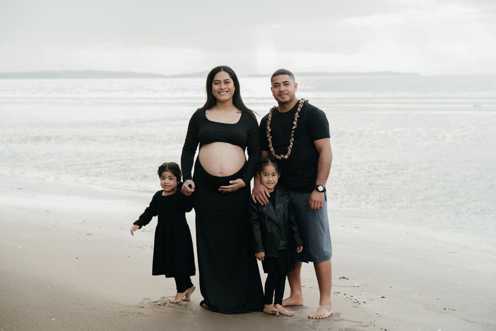 A family stands together on a misty beach with waves crashing behind them.