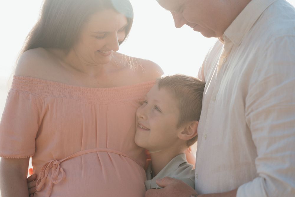 Family shares tender moment together in soft glowing sunlight.