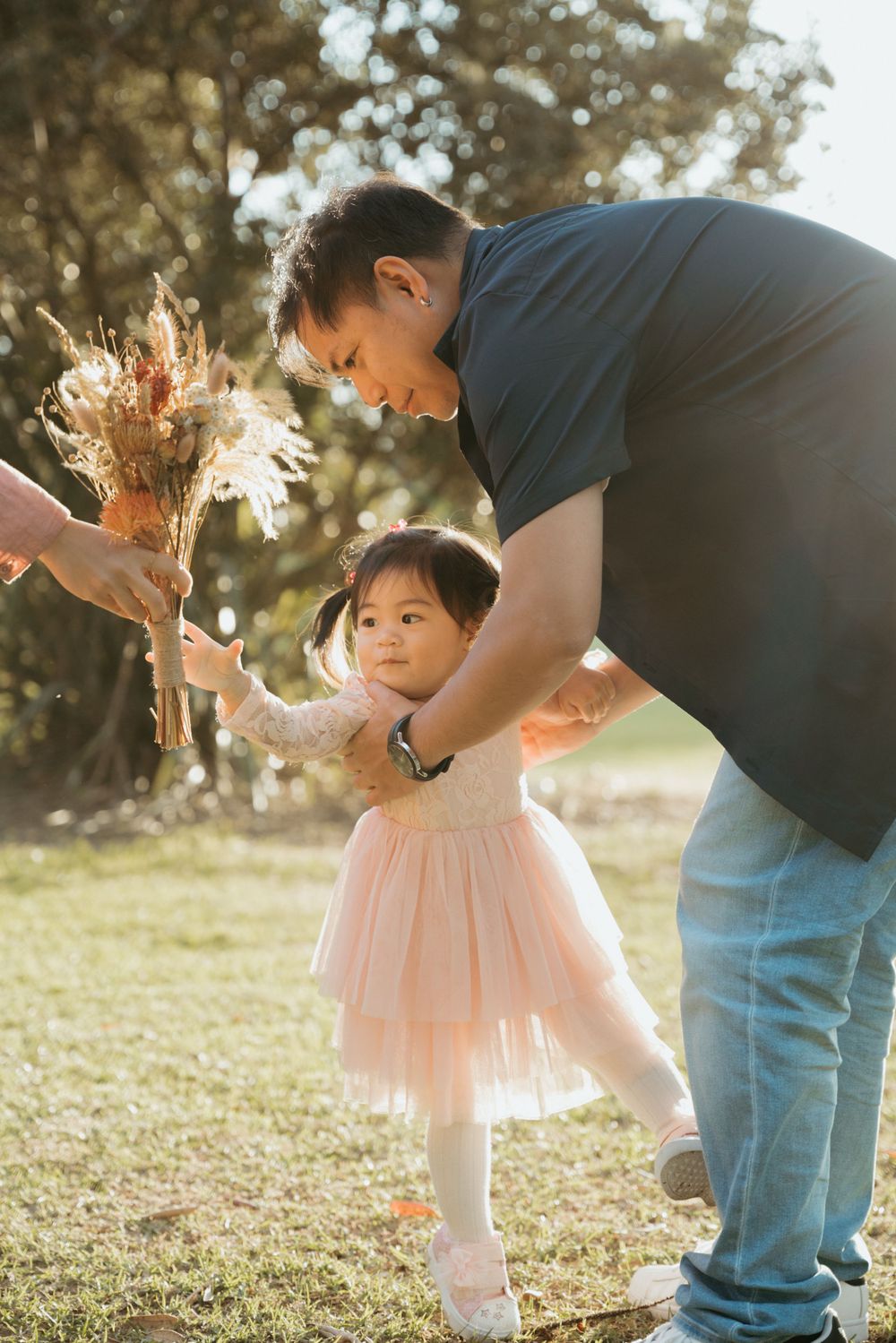 A tender moment between parent and child dancing with dried flowers in sunlit garden.