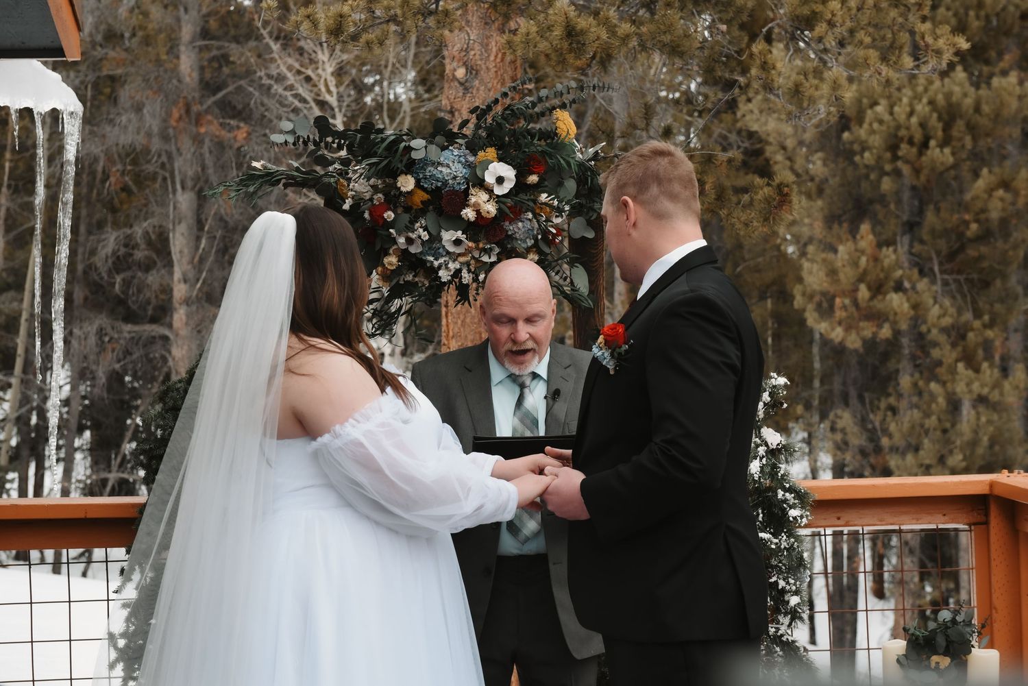 Four connected photos show winter wedding moments on a snowy outdoor deck with celebrants and a bride in white.