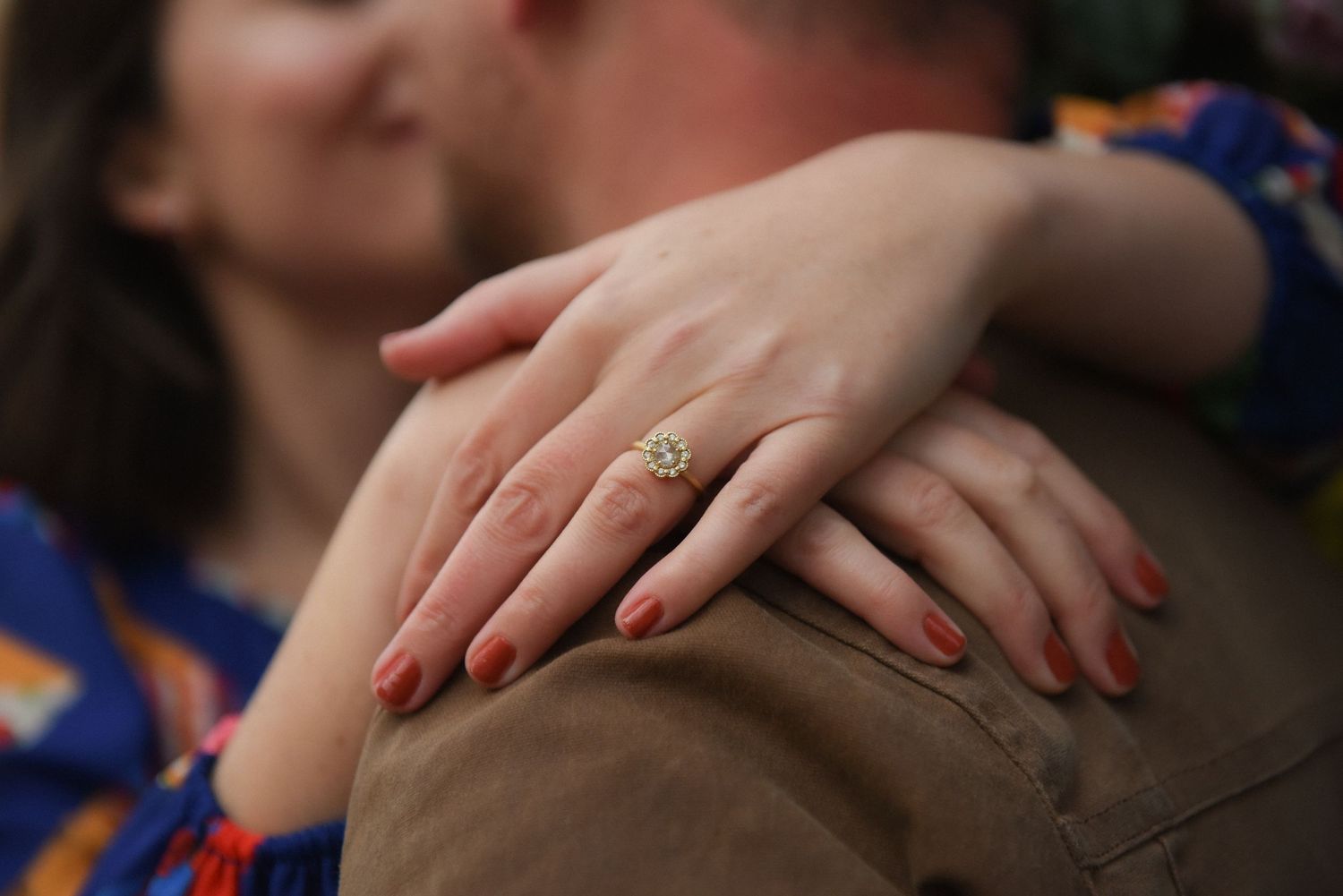 Several hands wearing bright red nail polish reach toward the center of the frame against a dark background.