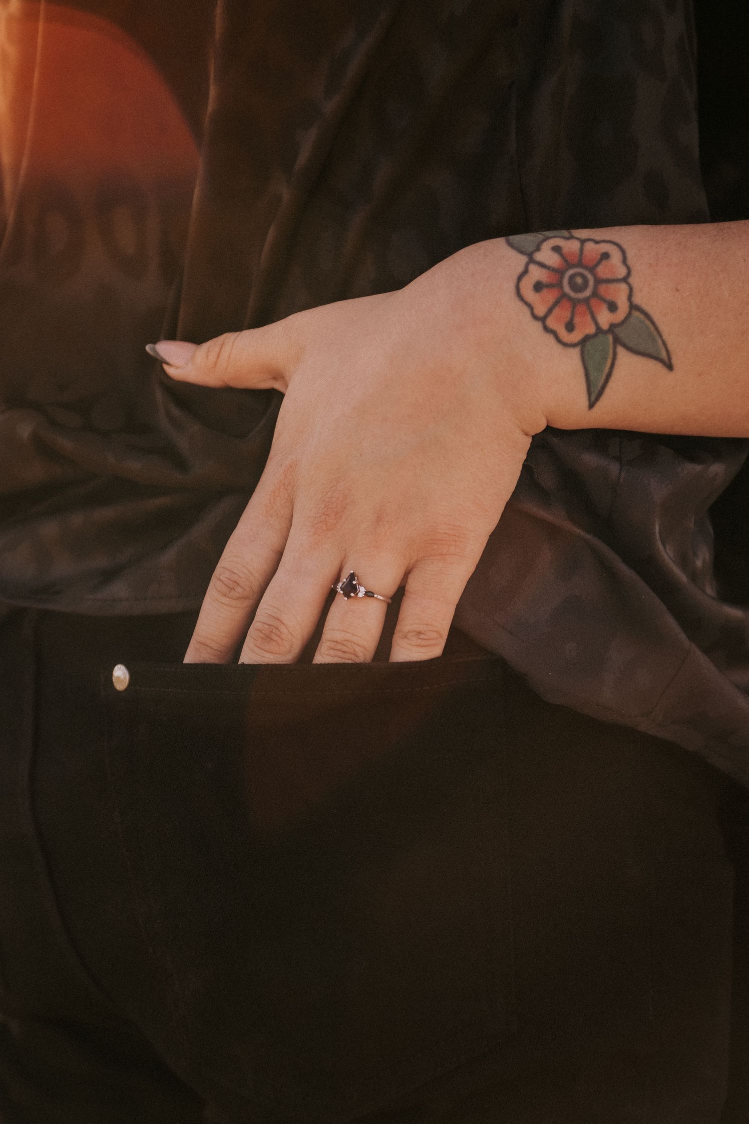 Close-up of a hand wearing an engagement ring and displaying a small tattoo tucked in a pants pocket. LGBT wedding photographer Albuquerque.