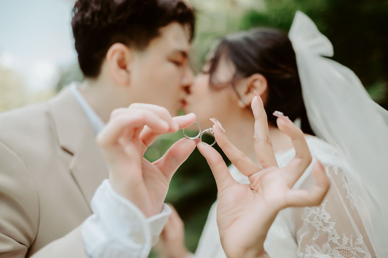 Close-up artistic photo showing hands holding wedding rings in soft natural lighting.