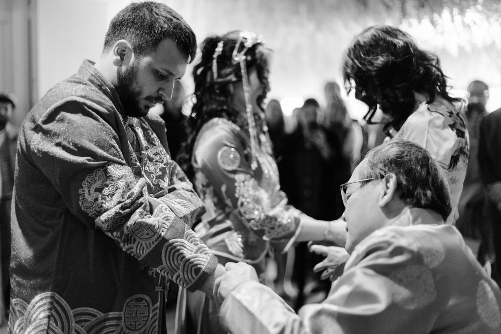 Black and white photo of a religious ceremony with a bearded priest in ornate robes performing a blessing.