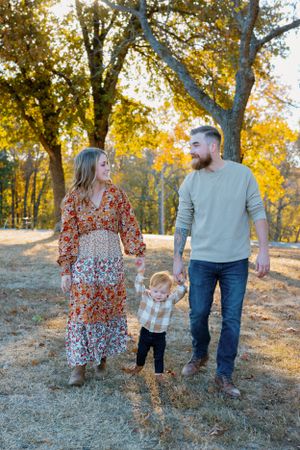 Family walking together among autumn trees in golden afternoon light.