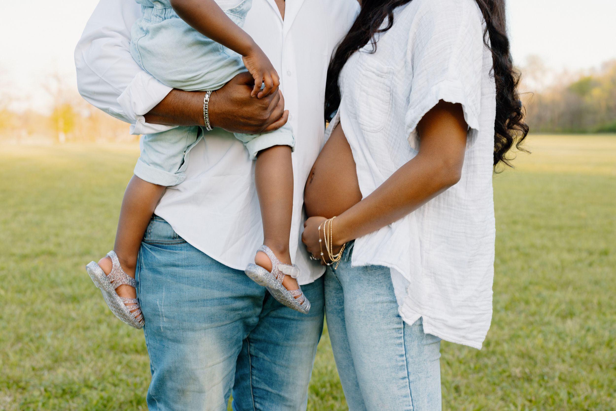 Close-up of casual denim and white outfits showing affectionate family moment.
