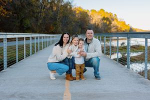 Family portrait on wooden pier during golden hour by waterfront.