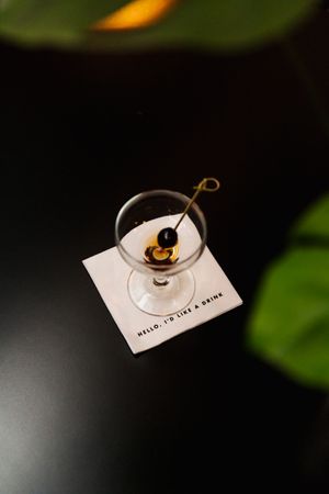 Martini glass with garnish on branded cocktail napkin.