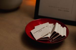 White business cards displayed on red ceramic plate.