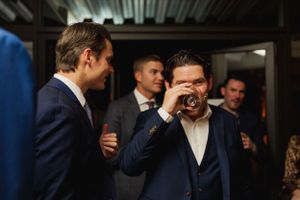 Wedding guests in formal attire sharing laughs in dimly lit room.