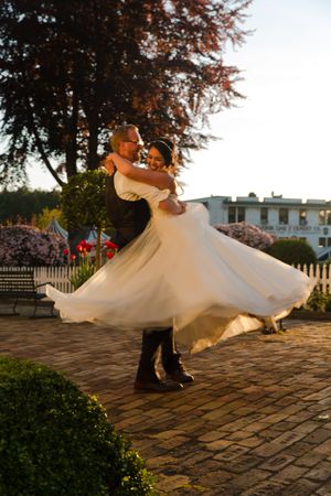 A couple dances on a stone patio at sunset, with the bride's dress twirling dramatically.