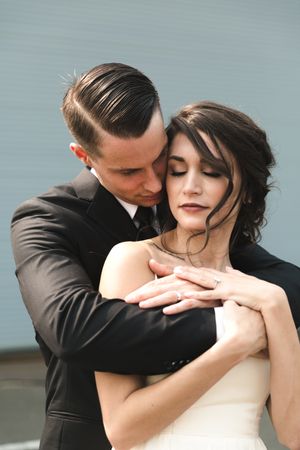 A romantic wedding portrait shows a couple in an intimate embrace, with the bride in white and groom in black.