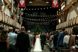 Wedding ceremony in a rustic venue with barrel walls and string lights creating a warm ambiance.