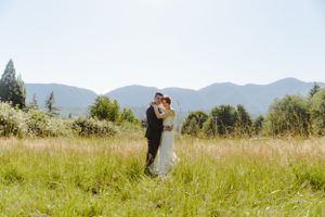 A couple shares a romantic moment in a mountain meadow on their wedding day.
