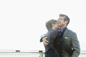 Romantic embrace between two people in formal attire against bright sunlight.