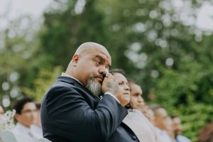 Emotional wedding guest wiping tears during outdoor ceremony.
