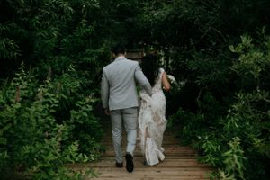 A couple walking away on a wooden boardwalk surrounded by lush green foliage.