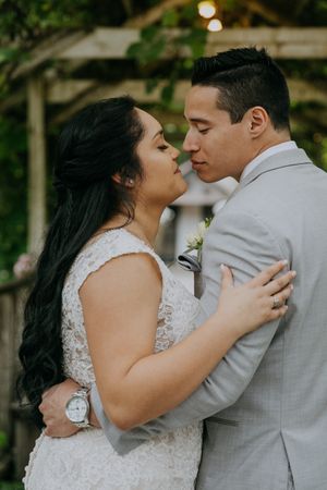 An intimate portrait of a couple in wedding attire sharing a close moment outdoors.