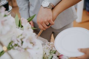 Elegant place setting with white plates and flowers being arranged at a formal event.