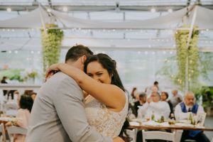 Intimate dance moment under a white tent with hanging greenery at a wedding reception.