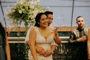 Joyful laughter shared during an outdoor wedding reception with hanging floral decorations.